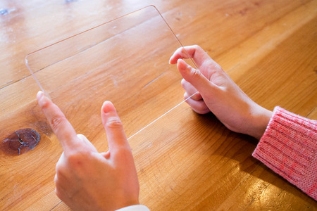 Isolated shot of hands holding/grabbing and operating/using transparent tablet PC with both handsの写真素材