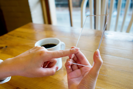 Isolated shot of hands holding/grabbing and operating/using transparent smart phoneの写真素材