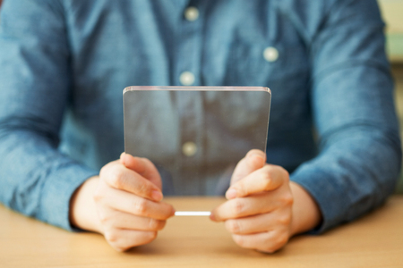 Isolated shot of hands holding/grabbing and operating/using transparent tablet PC with both hands