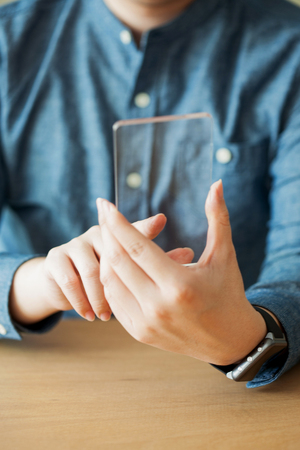 Isolated shot of hands holding/grabbing and operating/using transparent smart phoneの写真素材