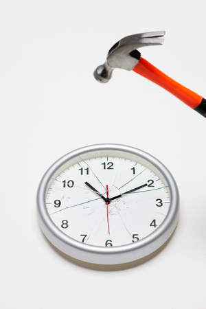 Damaged/Smashed/Broken round shape wall clock with a hammer in white backgroundの写真素材