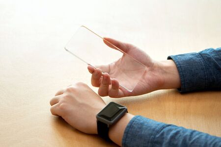 Isolated shot of hands operating/using transparent smart phone and smart watch together