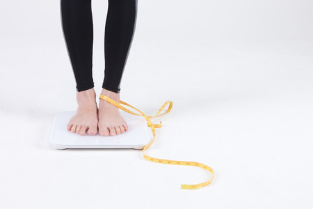 Healthy life of a beautiful Asian woman, Young woman in working out clothes posing with measuring tape - isolated on whiteの写真素材