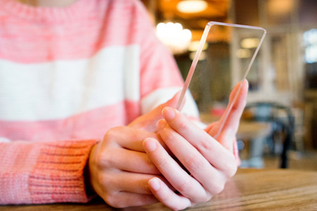 Isolated shot of hands holding/grabbing and operating/using transparent smart phoneの写真素材
