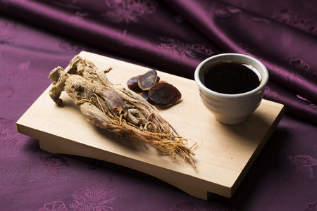 Dried red ginseng, honeyed red ginseng slices and red ginseng extract on a wooden boardの写真素材