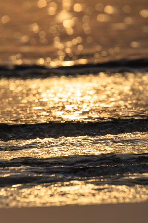 Close up shot of glowing surface of wavy sea water at sunsetの写真素材