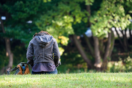 Back shot of a woman sitting down on green fieldの写真素材