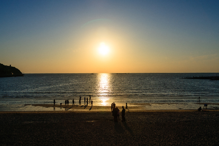 Scenery of people playing on the sandy beach at sunsetの写真素材