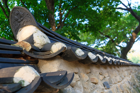 Close up shot of tiled roof stone wall fence with treesの写真素材