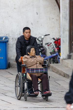 Suzhou, China - Man aiding his mother in wheelchairのeditorial素材