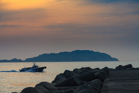 Life in island - Fish boat coming back into the port at sunsetのeditorial素材