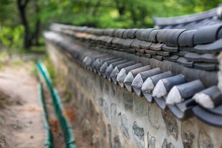Close up shot of tiled roof stone brick wall fence and water ditchの写真素材