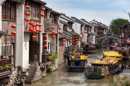 Suzhou, China - A couple of boats sailing on a canal between housesのeditorial素材
