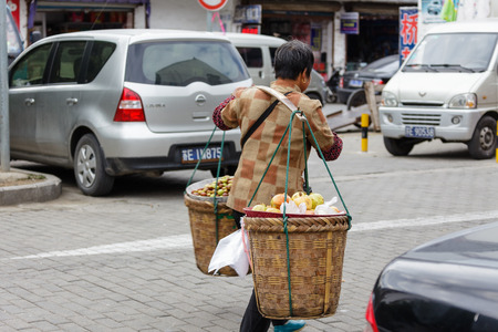 Suzhou, China - Old lady carrying a load across shoulderのeditorial素材