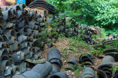 Stacked roof tiles with sand and grassesの写真素材