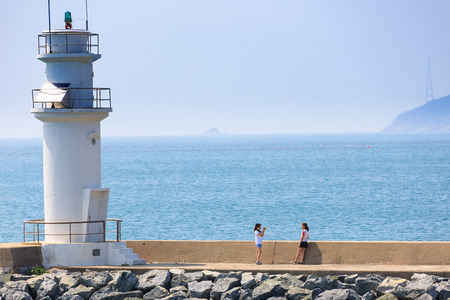 Slow city island-Two Korean girls taking pictures by the light houseのeditorial素材