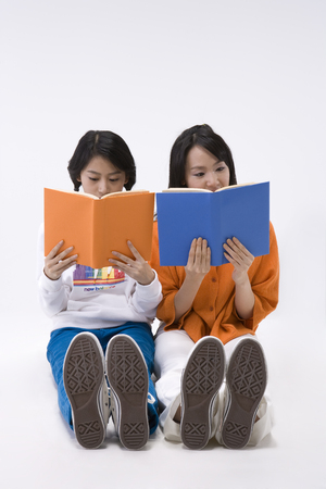 Asian women posing with books in a studioの写真素材