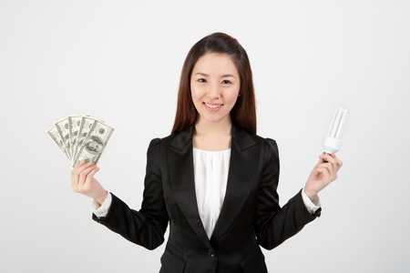 Female Asian in business suit posing with money and lampの写真素材