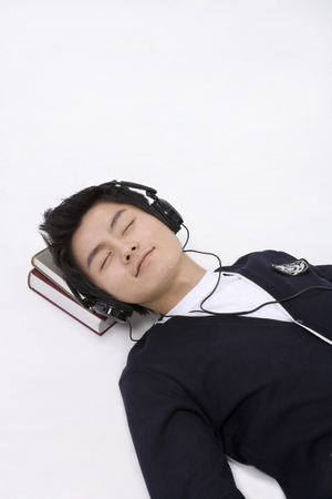 Asian man posing like sleeping with books in a studioの写真素材
