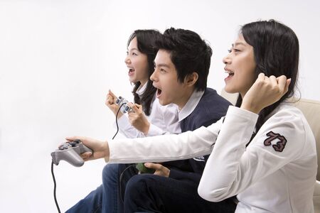 Two Asian women and a man posing together in a studio as sitting on couchの写真素材