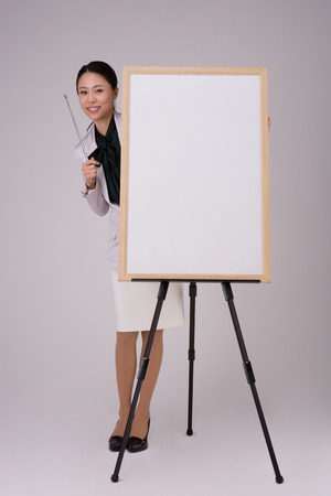 Female business person posing in a studio with empty white boardの写真素材