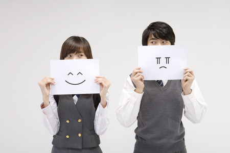 Asian male and female students in school uniforms posing in a studio with emoticons