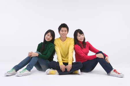 Two Asian women and a man posing in a studio as sitting down on the floorの写真素材