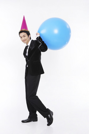 Male Asian in suit posing in a studio with balloonsの写真素材