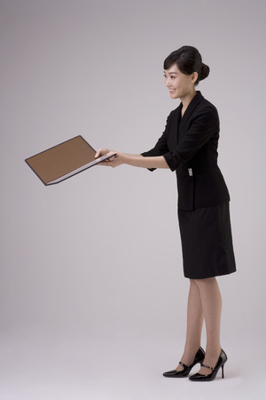 Asian woman in dress suit posing in a studio with a menuの写真素材
