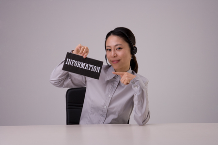 Asian female in suit sitting at information deskの写真素材
