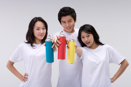 Two Asian women and a man posing in a studio with paint spraysの写真素材