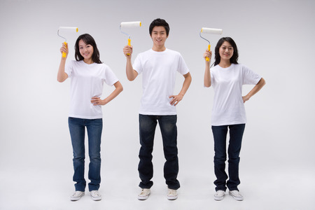 Two Asian women and a man posing in a studio with paint rollers/brushesの写真素材
