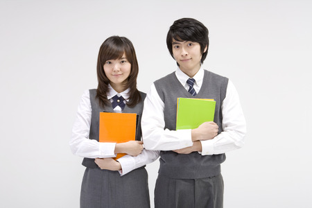 Asian male and female students in school uniforms posing in a studio with booksの写真素材