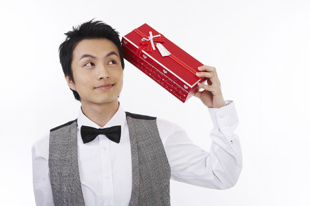 Male Asian in suit posing in a studio with giftboxの写真素材