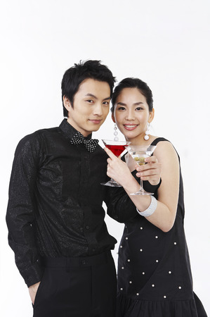 Dressed up Asian couple posing in a studio with cocktailsの写真素材