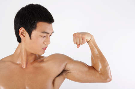 Young Asian male in training suits demonstrating exercise movements in a studioの写真素材