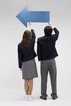 Asian male and female students posing in a studio with arrow propsの写真素材