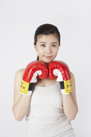 Young Asian female in yoga suits posing in a studio with boxing glovesの写真素材