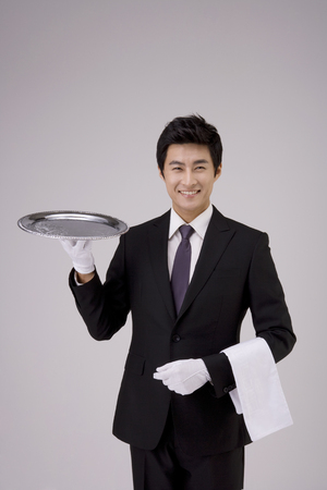 Asian man in black suit posing in a studio with an empty trayの写真素材