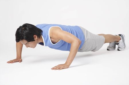 Young Asian male in training suits demonstrating exercise movements in a studio
