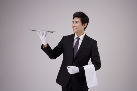 Asian man in black suit posing in a studio with an empty trayの写真素材