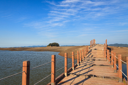 Close up shot of wooden bridge linking to rock island at low tideの写真素材