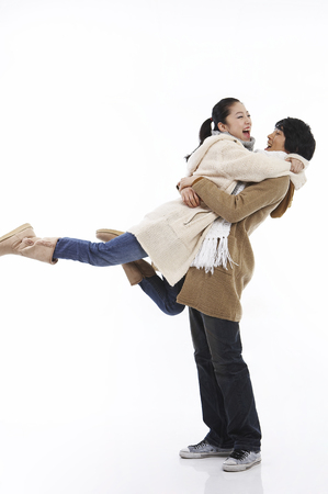 Young Asian couple in winter outfit posing in a studioの写真素材