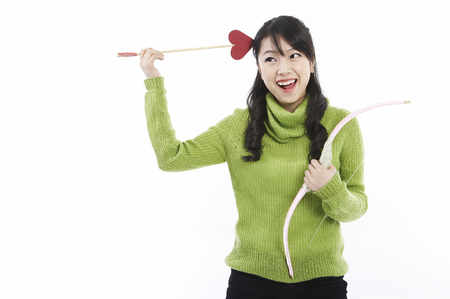 Young female Asian posing in a studio with cupid heart arrowの写真素材
