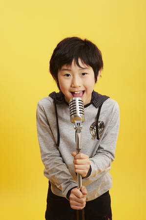 Young Aisn boy posing in a studio with microphoneの写真素材