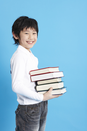 Young Asian boy posing in a studio with booksの写真素材