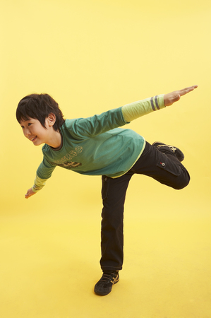 Young Asian boy posing in a studio in motion like a airplaneの写真素材