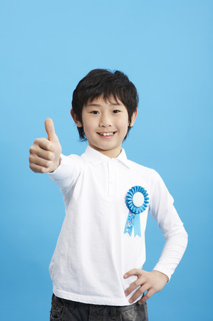 Young Asian boy posing in a studio with flower badgeの写真素材