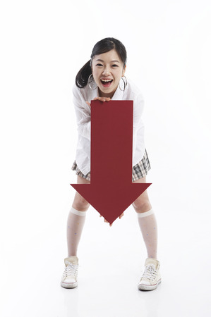Young female fashionable Asian posing in a studio with arrow shape propsの写真素材