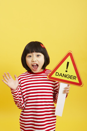 Young Asian girl posing in a studio with danger signの写真素材
